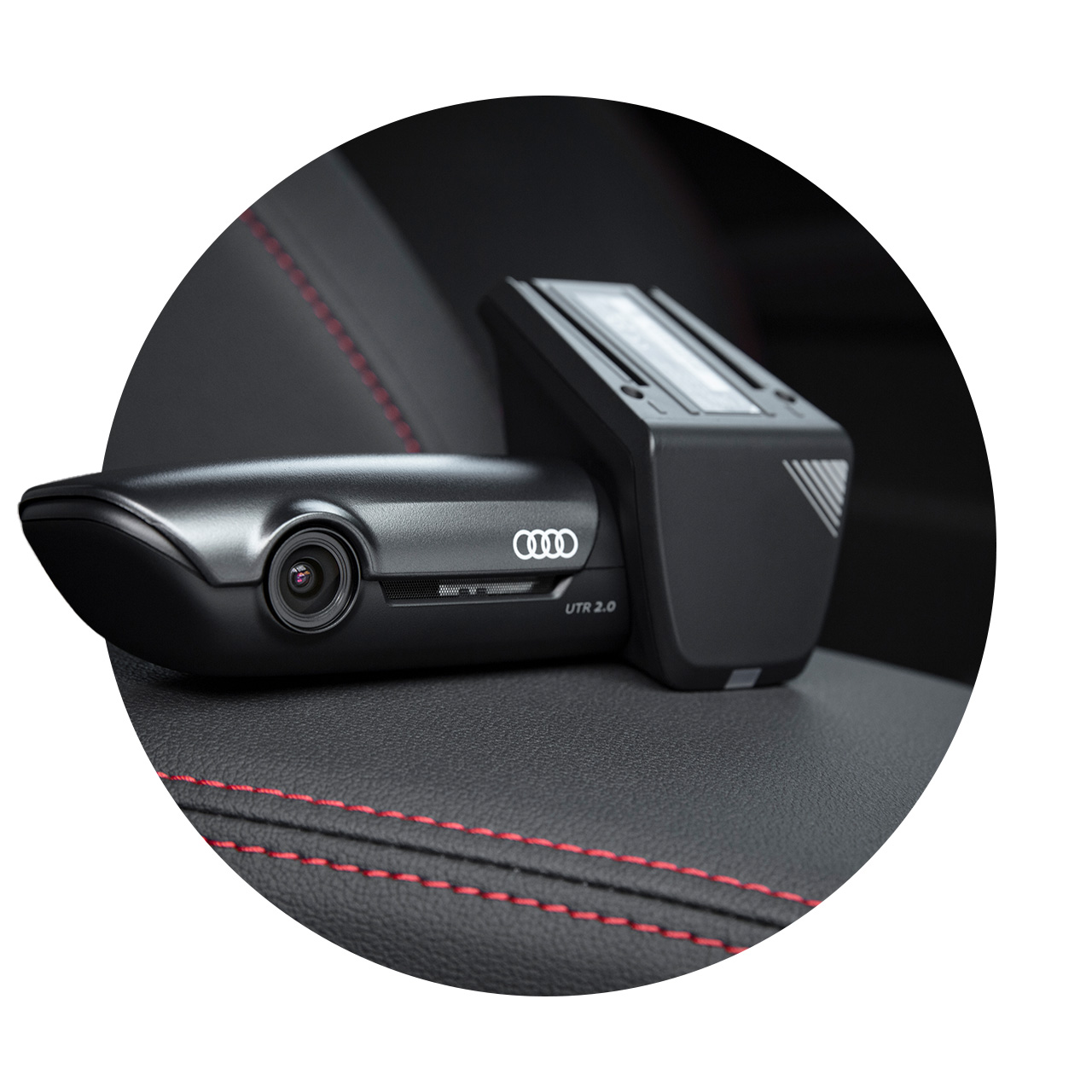 Schwarze Audi-Dashcam UTR 2.0 liegt auf schwarzem Autositz mit roter Ziernaht.